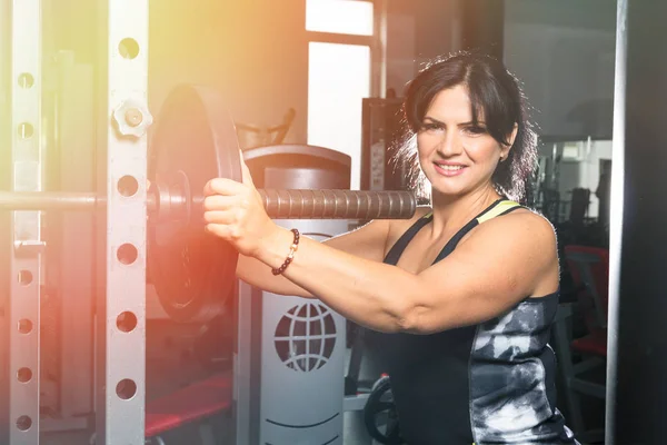 Mujer más tamaño en el gimnasio haciendo ejercicios con barra de levantamiento de pesas, f —  Fotos de Stock