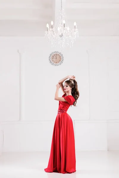 Mujer elegante en vestido largo rojo de pie en habitación blanca. Copiar spa —  Fotos de Stock