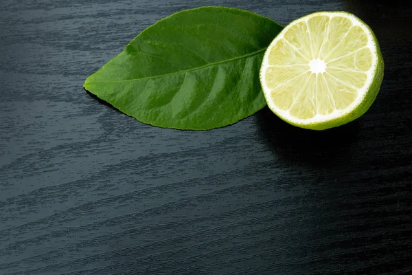 Healthy food and vitamins: green fresh lime with leaf on black t — Stock Photo, Image