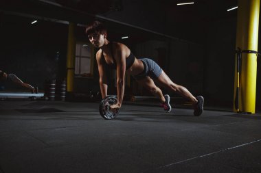 fitness kız ile tekerlek karanlık salonda, spo salonunda egzersizleri yapıyor