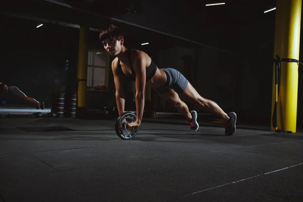 Fitness lány csinál ünnepély-ban tornaterem kerék sötét teremben, spo — Stock Fotó