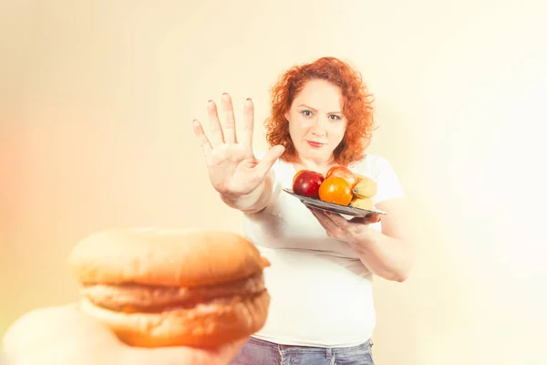 Mulher grande comer fast food. Menina gorda de cabelo vermelho com hambúrguer. Insalubre — Fotografia de Stock