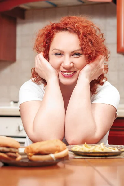 Mulher grande comer fast food. Cabelo vermelho menina gorda com hambúrguer, batata a — Fotografia de Stock