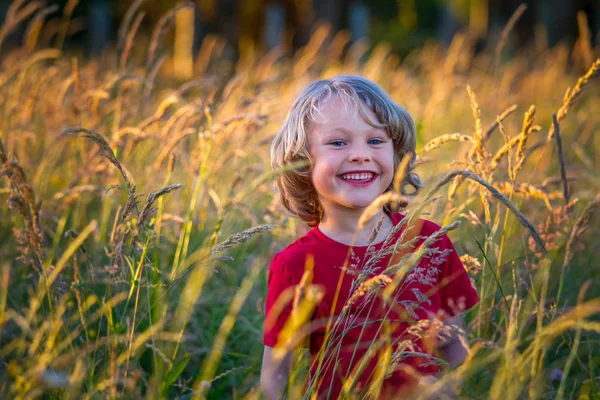 Mignon blonde enfant dans un champ au coucher du soleil — Photo