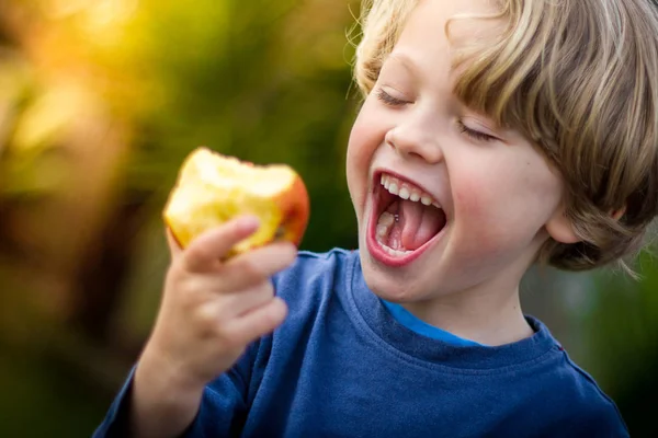 Bir elma bir ısırık almak sevimli sarışın çocuk Stok Fotoğraf
