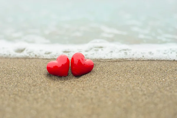 Två röda hjärtan på en bakgrund av stranden och havet — Stockfoto