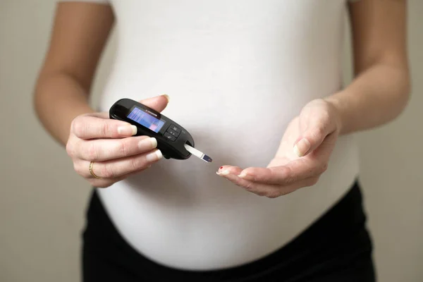 Diabetes test. Pregnant women checking sugar level with glucometer.