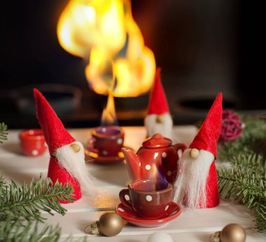Xmas süslemeleri ile şömine oturan ve içme Noel Baba'nın yardımcıları sıcak çay. Christmas fairy tail. 