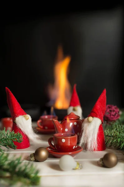 Santa's helpers sitting near fireplace with xmas decorations and drinking hot tea. Christmas fairy tail.