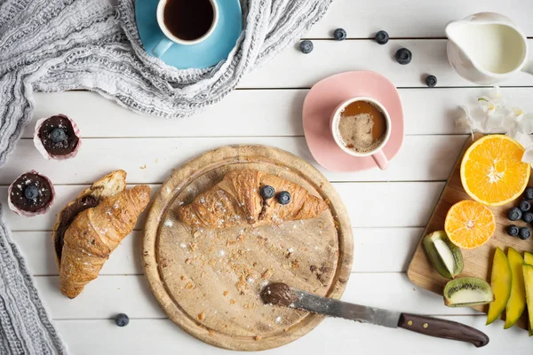 Πρωινό με καφέ, κρουασάν, μάφιν και φρούτα σε λευκό ξύλινο τραπέζι. — Φωτογραφία Αρχείου