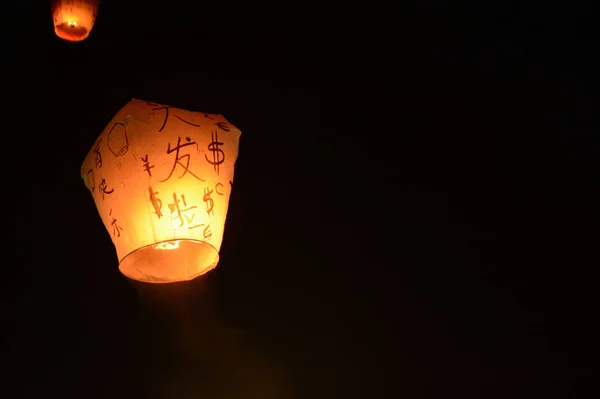 Sky lantern floating into the night sky at the festival in Pingxi, the Chinese text is a wish for money in the New Year — Stock Photo, Image