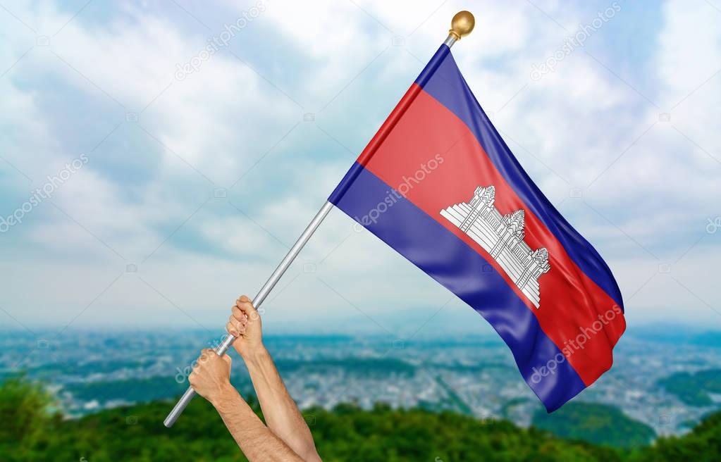 Young man's hands proudly waving the Cambodia national flag in the sky, part 3D rendering