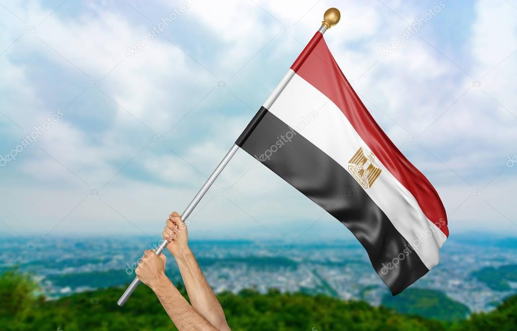 Young man's hands proudly waving the Egypt national flag in the sky, part 3D rendering