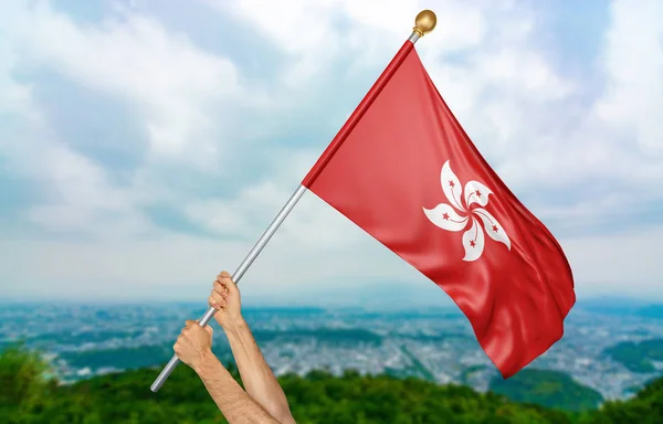 Manos de hombre joven orgullosamente ondeando la bandera nacional de Hong Kong en el cielo, parte 3D representación —  Fotos de Stock