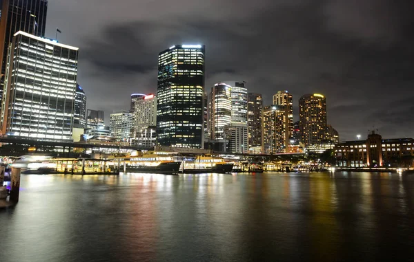 Circular Quay ferry docks in front of the central business district at night in Sydney, Australia