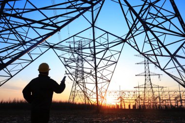 Elektrik işçileri ve pilon silueti