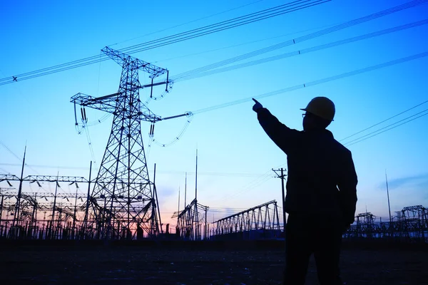 Elektrik işçileri ve pilon silueti
