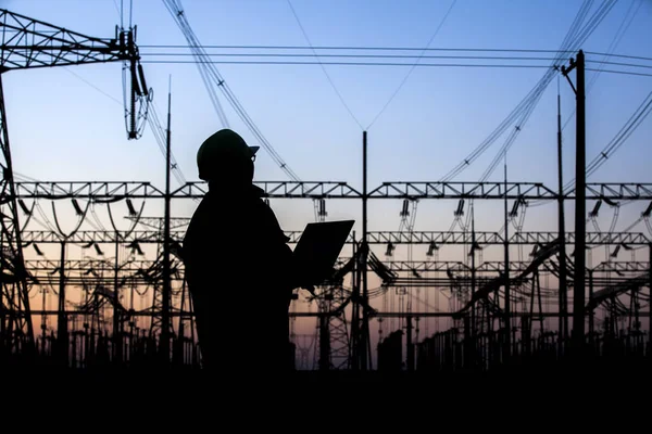 Electricity workers and pylon silhouette