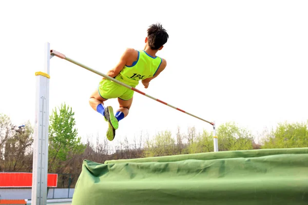 Een mannelijke atleet is op de hoge sprong — Stockfoto