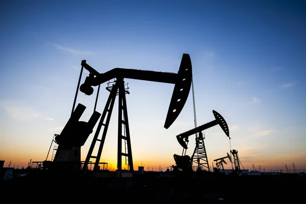 Scena del campo petrolifero, la sera dell'unità di pompaggio del fascio nella silhouette — Foto Stock