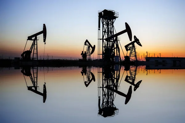 Escena del campo petrolífero, la noche de la unidad de bombeo de haz en silueta — Foto de Stock