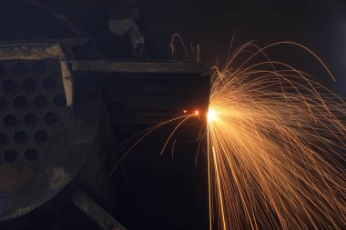 Atölye kaynakçısı metali kesiyor.