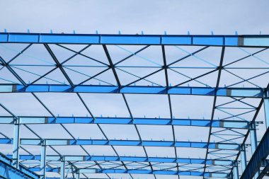 Çelik iskelet yapısı mavi gökyüzünün altında.