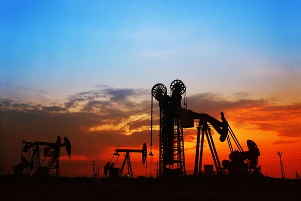 The evening of the oilfield, pumping unit and the silhouette of oilfield derrick