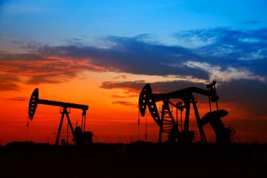 Petrol sahası sahnesi, ışın pompalama ünitesinin siluette olduğu gece.