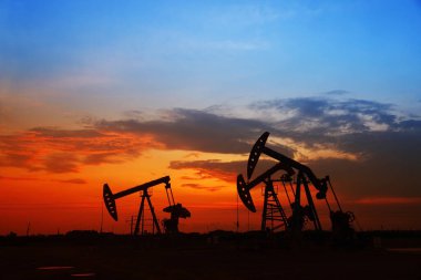 Petrol sahası sahnesi, ışın pompalama ünitesinin siluette olduğu gece.