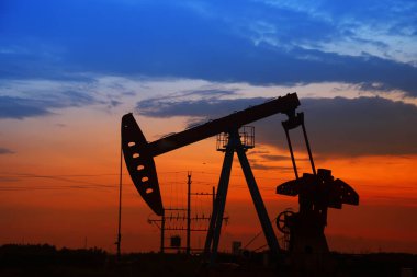 Petrol sahası sahnesi, ışın pompalama ünitesinin siluette olduğu gece.