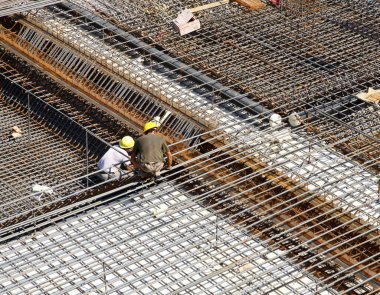 İnşaat alanında beton döşeme için takviye metal iskeleti yapan işçiler