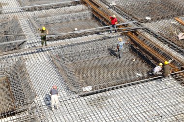 İnşaat alanında beton döşeme için takviye metal iskeleti yapan işçiler