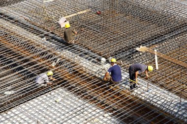 İnşaat alanında beton döşeme için takviye metal iskeleti yapan işçiler