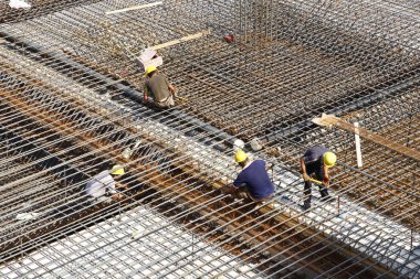 İnşaat alanında beton döşeme için takviye metal iskeleti yapan işçiler