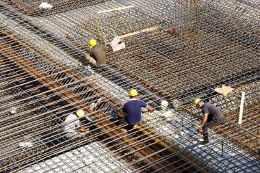 İnşaat alanında beton döşeme için takviye metal iskeleti yapan işçiler