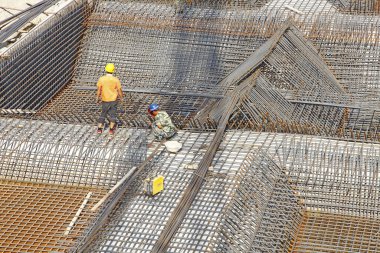 İnşaat alanında beton döşeme için takviye metal iskeleti yapan işçiler