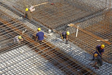 İnşaat alanında beton döşeme için takviye metal iskeleti yapan işçiler