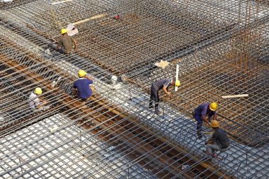 İnşaat alanında beton döşeme için takviye metal iskeleti yapan işçiler
