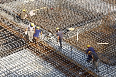 İnşaat alanında beton döşeme için takviye metal iskeleti yapan işçiler