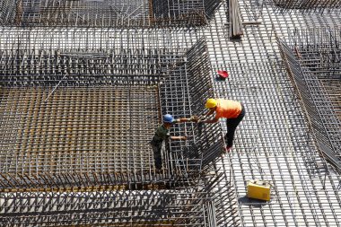 İnşaat alanında beton döşeme için takviye metal iskeleti yapan işçiler