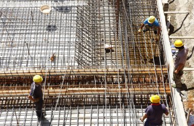 İnşaat alanında beton döşeme için takviye metal iskeleti yapan işçiler