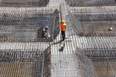 İnşaat alanında beton döşeme için takviye metal iskeleti yapan işçiler