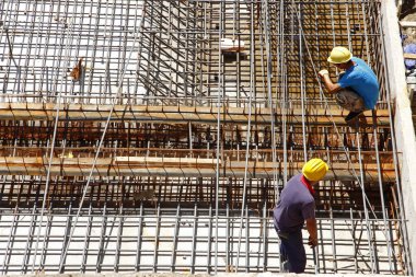 İnşaat alanında beton döşeme için takviye metal iskeleti yapan işçiler