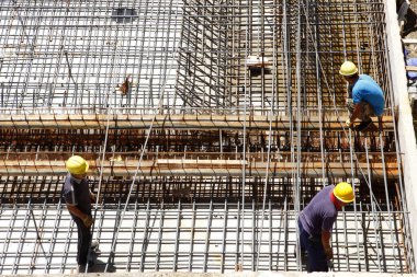İnşaat alanında beton döşeme için takviye metal iskeleti yapan işçiler