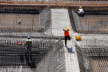 İnşaat alanında beton döşeme için takviye metal iskeleti yapan işçiler