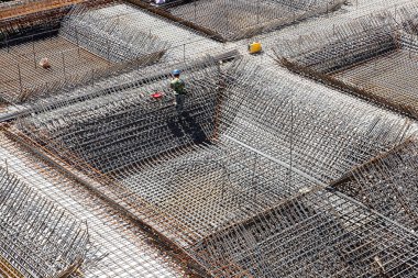 İnşaat alanında beton döşeme için takviye metal iskeleti yapan işçiler