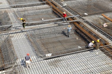 İnşaat alanında beton döşeme için takviye metal iskeleti yapan işçiler