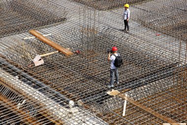 İnşaat alanında beton döşeme için takviye metal iskeleti yapan işçiler