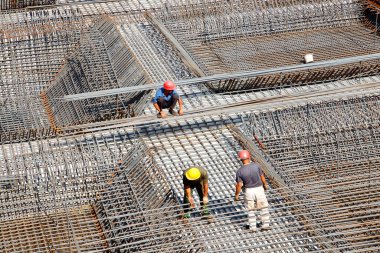 İnşaat alanında beton döşeme için takviye metal iskeleti yapan işçiler